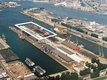 The photo is taken from above. There are four land parts with buildings and cars on them. The parts are seperated by water.