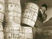Historic sepia photo of port workers standing next to large coffee barrels.
