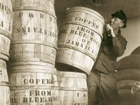 Historic sepia photo of port workers standing next to large coffee barrels.