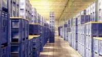 Warehouse aisle with high storage racks and palletized goods on both sides.
