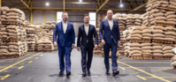 Drie directeuren lopen samen door een gang in een magazijn.