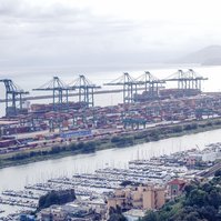 Luchtfoto van een containerterminal met gestapelde containers en kranen langs het water.