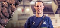 Man with brown hair in a ponytail smiling at the camera in a warehouse.