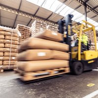 Forklift transporting large jute bags inside a warehouse.  🇩🇪 Deutsch:
