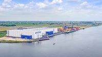 Three warehouses with the Vollers logo on them. On the right is the sea.