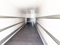 Interior of an empty truck trailer with loading rails along the side walls.
